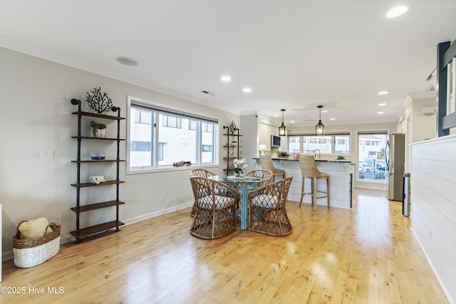 dining area with ornamental molding, a healthy amount of sunlight, and light hardwood / wood-style flooring