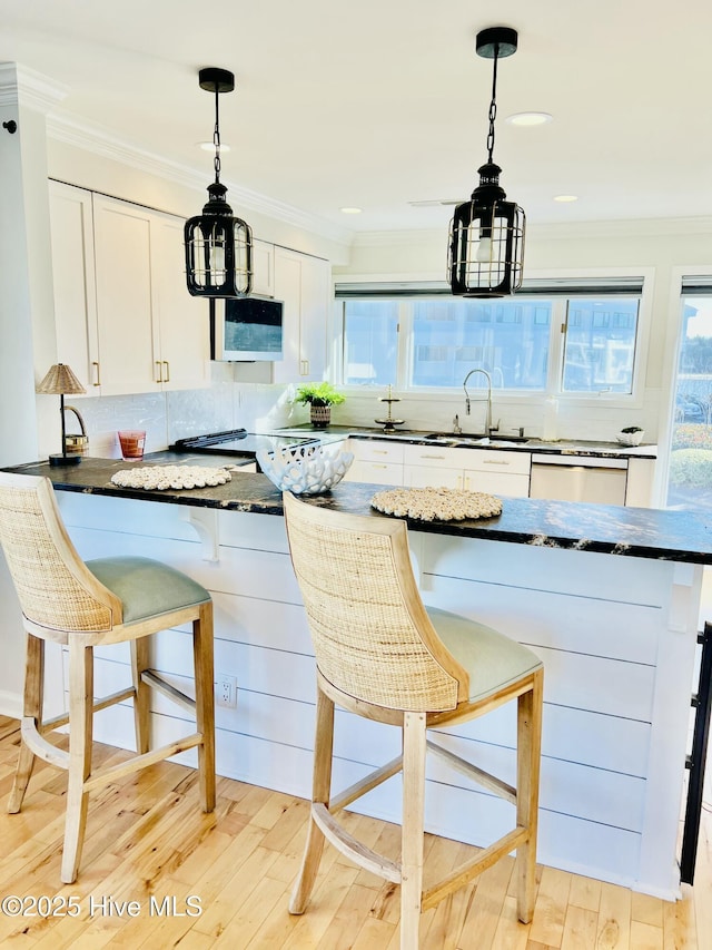 kitchen with decorative light fixtures, sink, a breakfast bar area, and white cabinets