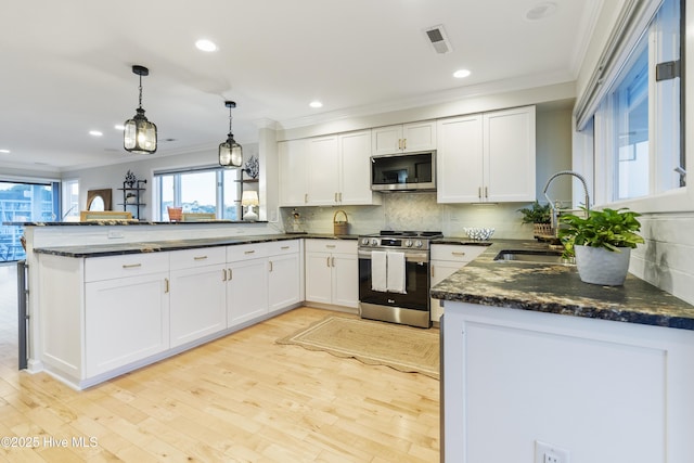 kitchen featuring appliances with stainless steel finishes, kitchen peninsula, hanging light fixtures, and white cabinets