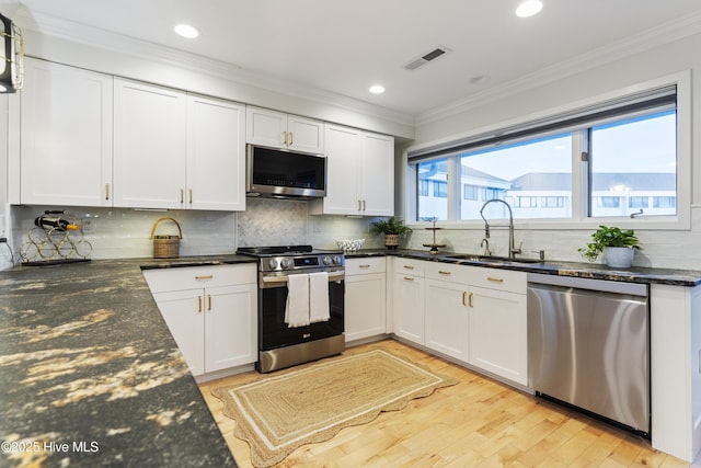 kitchen featuring sink, white cabinetry, dark stone countertops, stainless steel appliances, and light wood-type flooring