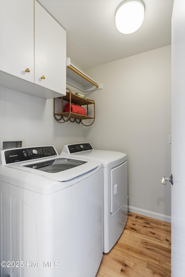 washroom with cabinets, washer and clothes dryer, and light hardwood / wood-style floors