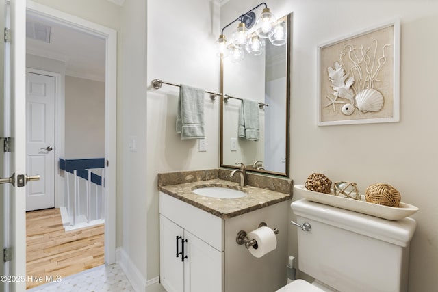 bathroom featuring vanity, ornamental molding, hardwood / wood-style floors, and toilet