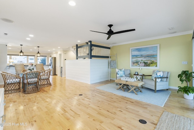 living room with crown molding, light hardwood / wood-style flooring, and ceiling fan