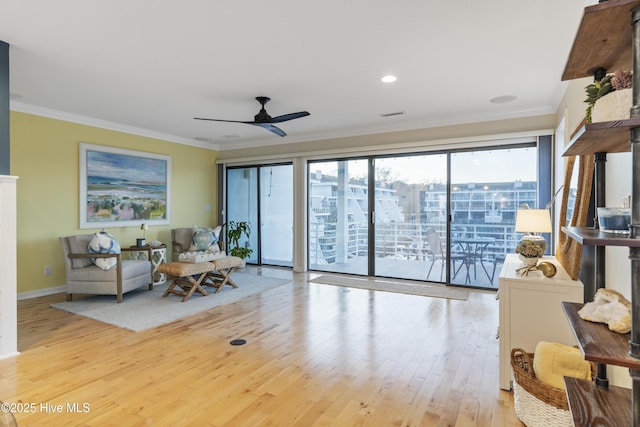 living room with ornamental molding, ceiling fan, and light hardwood / wood-style floors