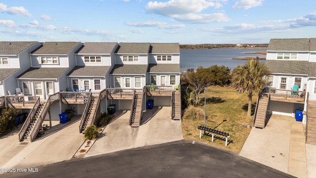 view of front of property featuring driveway, a residential view, stairway, a water view, and a carport