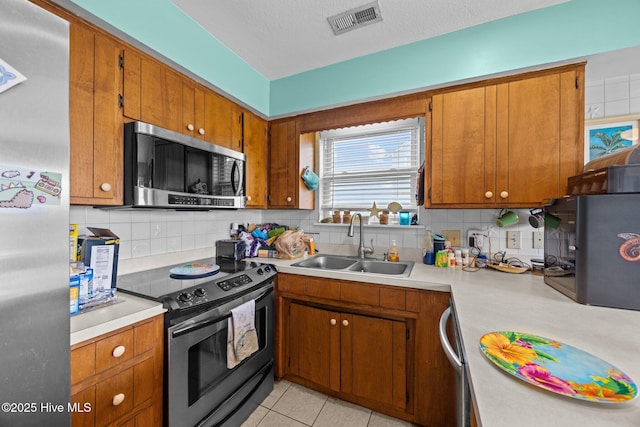 kitchen with stainless steel appliances, light countertops, a sink, and visible vents