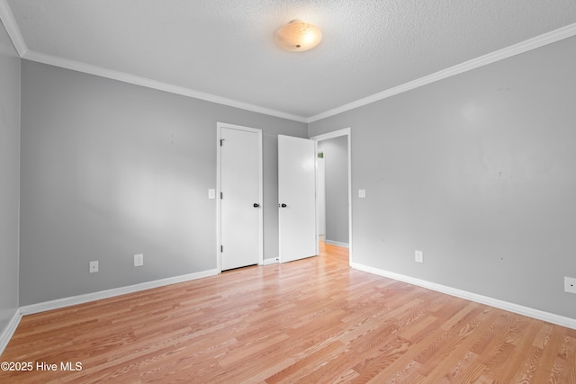 empty room featuring ornamental molding, light hardwood / wood-style flooring, and a textured ceiling