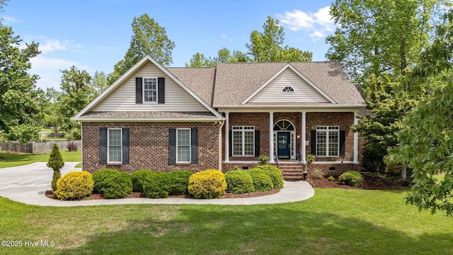 greek revival house featuring a front yard, crawl space, brick siding, roof with shingles, and fence