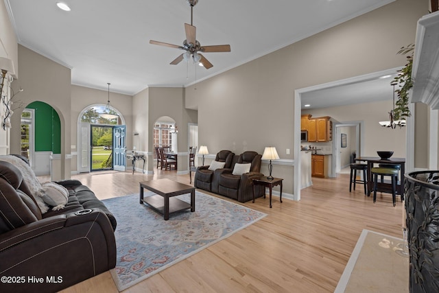 living area featuring crown molding, arched walkways, light wood-type flooring, recessed lighting, and a ceiling fan