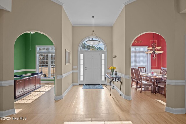 entrance foyer with ornamental molding, a chandelier, and light wood-type flooring