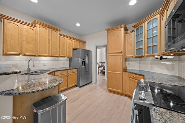 kitchen with electric stove, stainless steel fridge, backsplash, and a sink