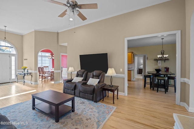 living room featuring a high ceiling, crown molding, ceiling fan, and light wood-type flooring