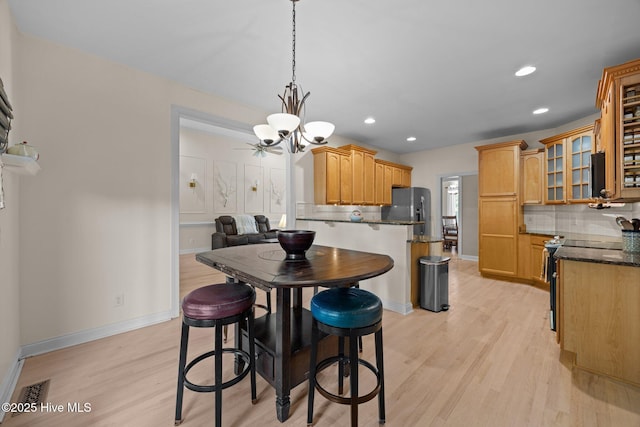 dining space with recessed lighting, a notable chandelier, baseboards, and light wood-type flooring