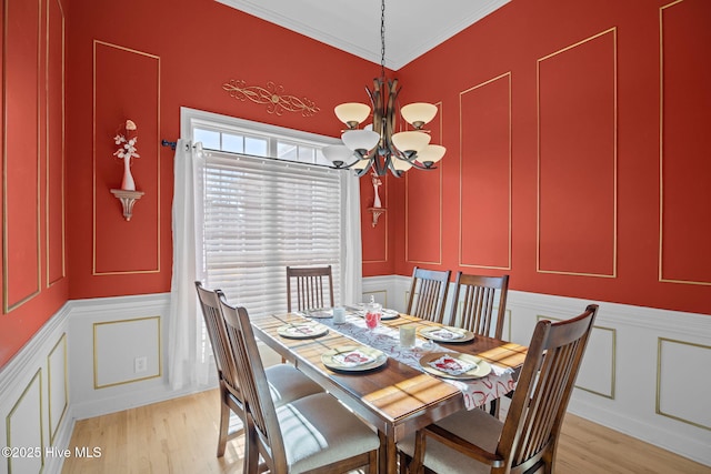 dining space with crown molding, an inviting chandelier, and light wood-type flooring