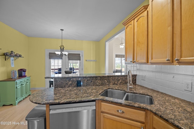 kitchen with pendant lighting, sink, dark stone counters, and dishwasher