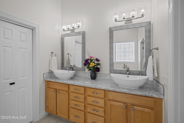 bathroom with tile patterned flooring, an inviting chandelier, a sink, and double vanity