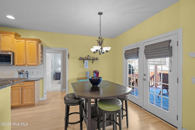 dining space featuring french doors, a chandelier, and light hardwood / wood-style flooring