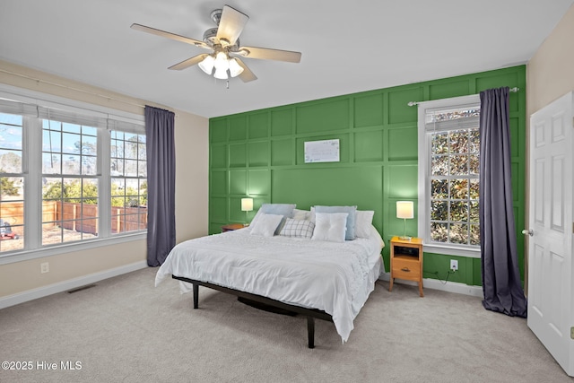 bedroom with carpet floors, a decorative wall, baseboards, visible vents, and a ceiling fan
