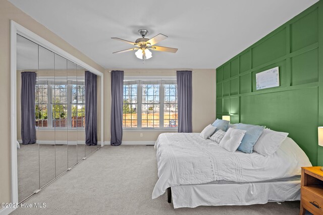 carpeted bedroom with a ceiling fan, baseboards, and multiple windows