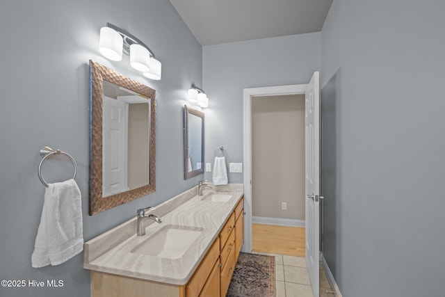 full bathroom featuring tile patterned flooring, baseboards, a sink, and double vanity