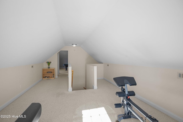 exercise area featuring visible vents, vaulted ceiling, carpet floors, and baseboards