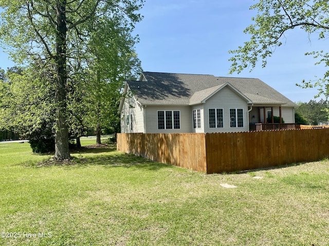 rear view of property featuring a yard and fence