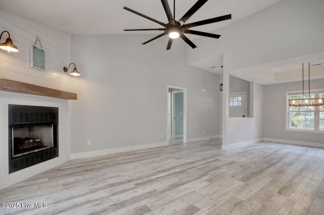 unfurnished living room featuring ceiling fan, high vaulted ceiling, and light wood-type flooring