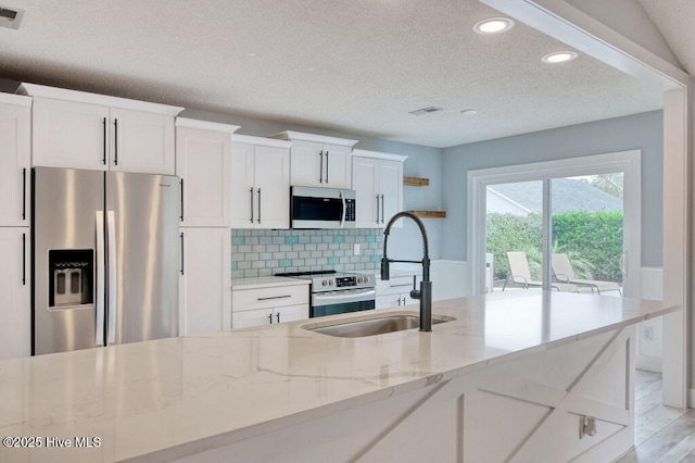 kitchen with white cabinetry, sink, backsplash, and stainless steel appliances