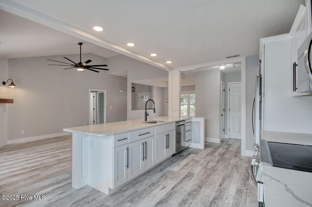 kitchen with lofted ceiling, sink, white cabinetry, stainless steel appliances, and light stone countertops