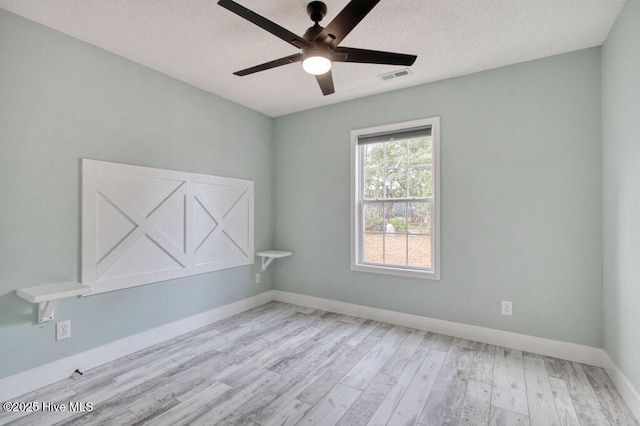 spare room with ceiling fan, light hardwood / wood-style floors, and a textured ceiling