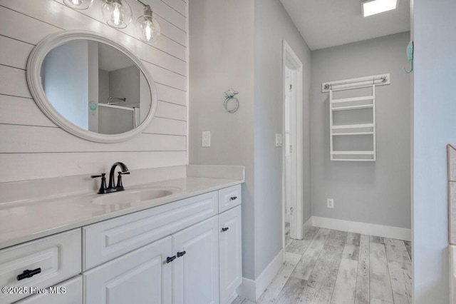 bathroom featuring vanity, an enclosed shower, hardwood / wood-style flooring, and wood walls