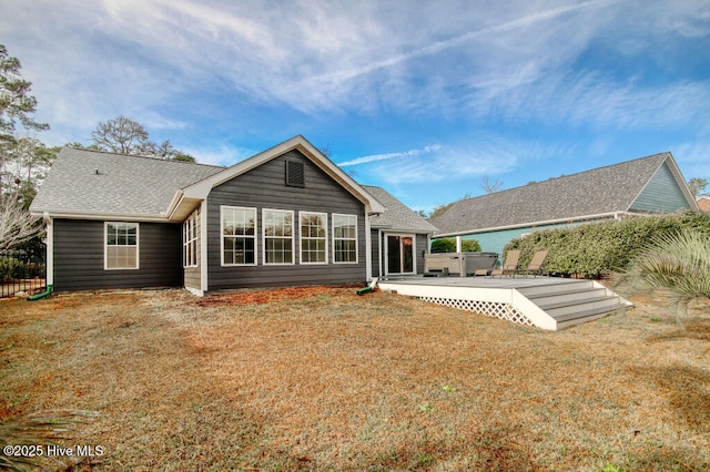 rear view of house with a wooden deck, a yard, and a jacuzzi