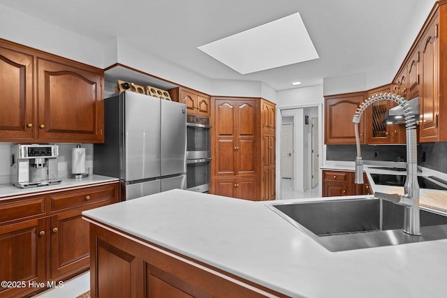 kitchen featuring stainless steel appliances, sink, and a skylight