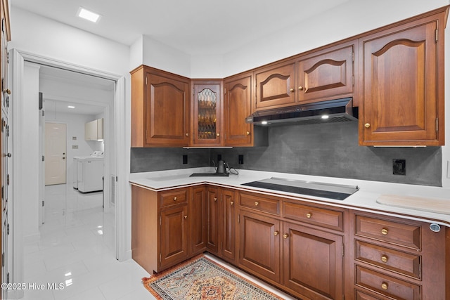 kitchen featuring light tile patterned flooring, separate washer and dryer, black electric stovetop, and backsplash