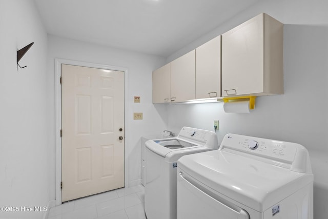 washroom featuring cabinets, light tile patterned floors, and washing machine and clothes dryer