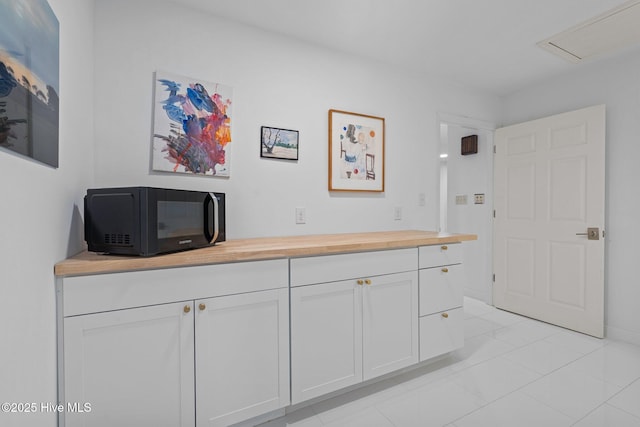 interior space featuring butcher block countertops, white cabinets, and light tile patterned flooring