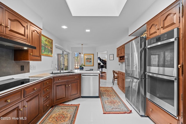 kitchen featuring stainless steel appliances, decorative light fixtures, kitchen peninsula, and sink