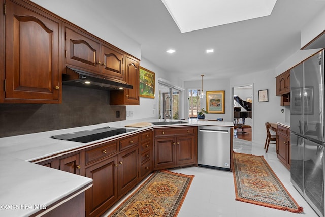 kitchen featuring sink, backsplash, stainless steel appliances, decorative light fixtures, and kitchen peninsula