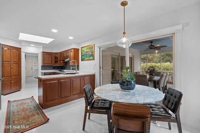 dining space featuring sink, ceiling fan, and a skylight