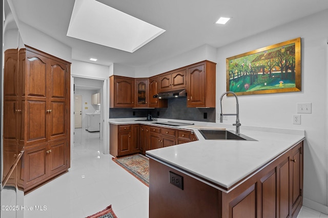 kitchen with washer and dryer, sink, backsplash, and kitchen peninsula