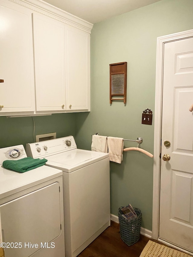 washroom with dark wood-type flooring, washer and clothes dryer, and cabinets