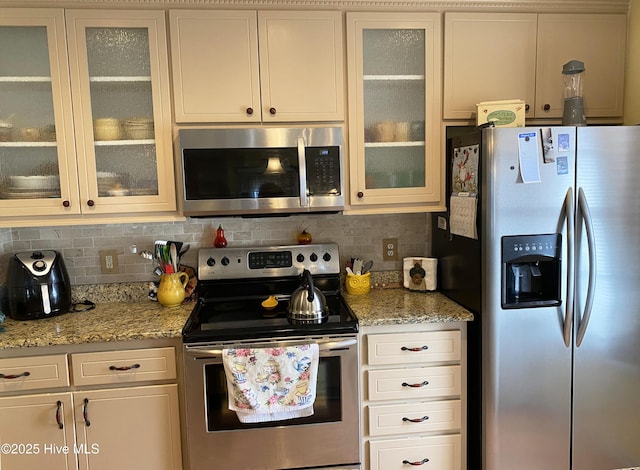 kitchen featuring tasteful backsplash, stainless steel appliances, light stone counters, and white cabinets