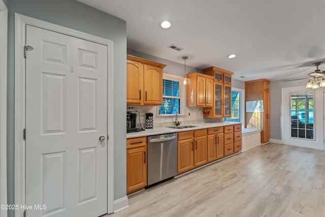 kitchen featuring tasteful backsplash, dishwasher, sink, light wood-type flooring, and decorative light fixtures