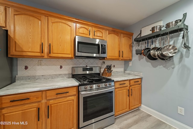 kitchen featuring stainless steel appliances, light hardwood / wood-style floors, and tasteful backsplash