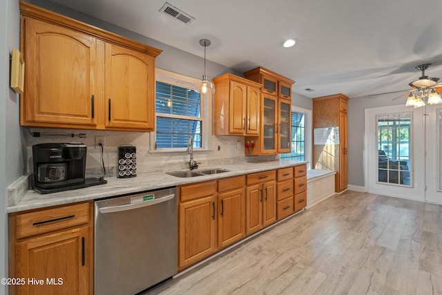 kitchen with stainless steel dishwasher, sink, decorative light fixtures, light hardwood / wood-style flooring, and backsplash