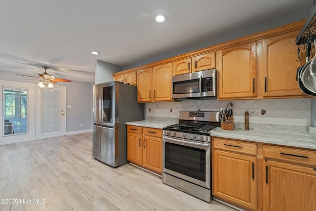 kitchen featuring stainless steel appliances, decorative backsplash, light hardwood / wood-style flooring, ceiling fan, and light stone counters