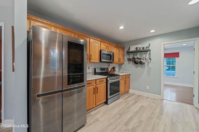 kitchen featuring tasteful backsplash, light hardwood / wood-style flooring, and appliances with stainless steel finishes