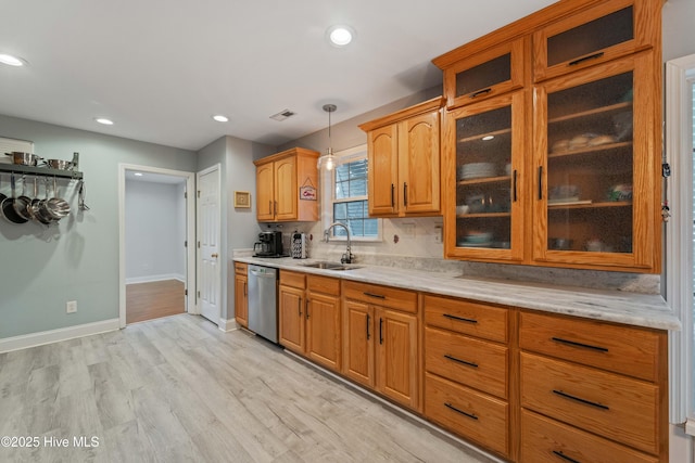 kitchen with stainless steel dishwasher, hanging light fixtures, sink, backsplash, and light hardwood / wood-style floors