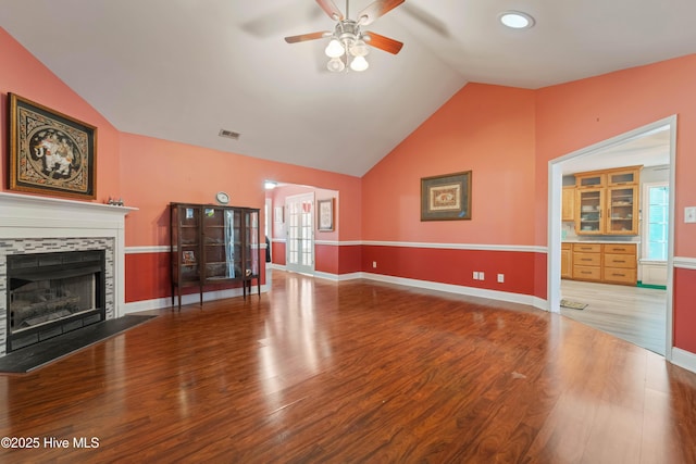 unfurnished living room with ceiling fan, wood-type flooring, a tile fireplace, and lofted ceiling