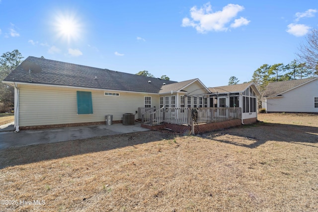 back of house with central air condition unit, a sunroom, a yard, and a patio